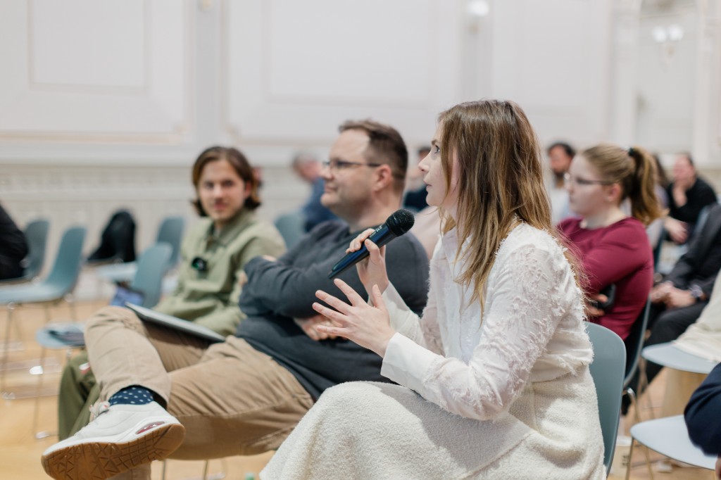 Collaborative workshop with participants around a table and whiteboards covered in sticky notes